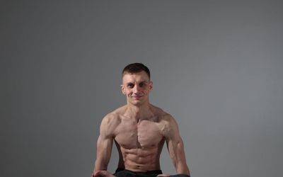 Athlete holding a difficult balance pose in a minimalist setting.
