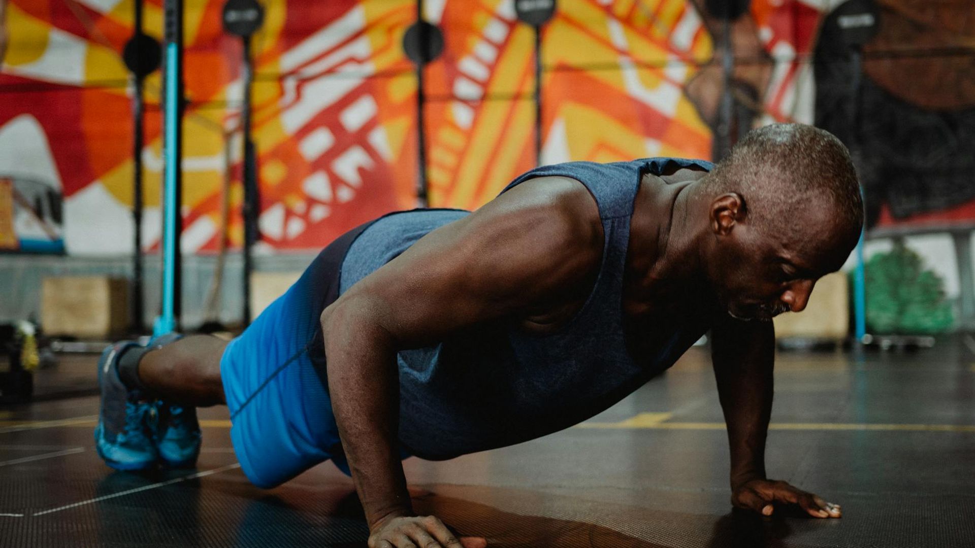 Focused man performing a bodyweight exercise in a minimalist dark gym.