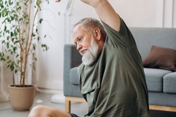 Man stretching on a yoga mat in a room with soft ambient light.